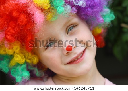 a cute little child dressed up in a clown costume and face paint and smiling