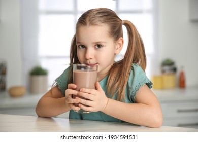 Cute Little Child Drinking Tasty Chocolate Milk In Kitchen