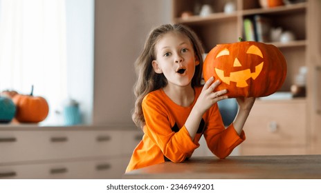 Cute little child girl with carving pumpkin. Happy family preparing for Halloween. 
