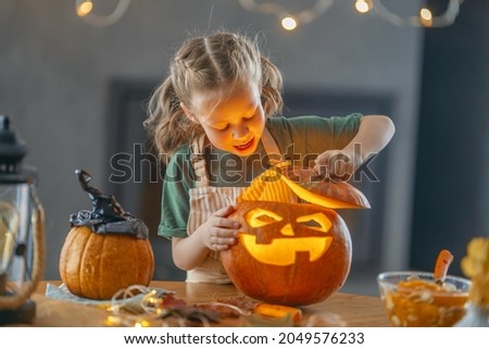 Cute little child girl with carving pumpkin. Happy family preparing for Halloween. 