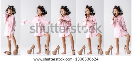 cute little child girl in hair curlers playing with her mother's clothes and shoes