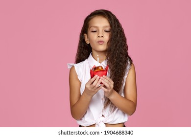 cute little child girl holding birthday cake with candle isolated on pink background