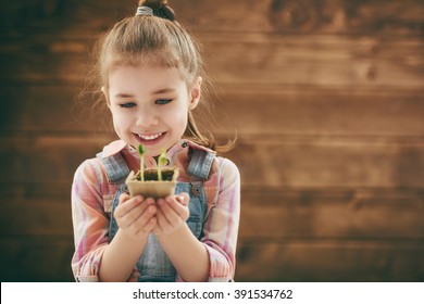 Cute little child girl planting seedlings. Fun little gardener. Spring concept, nature and care. - Powered by Shutterstock