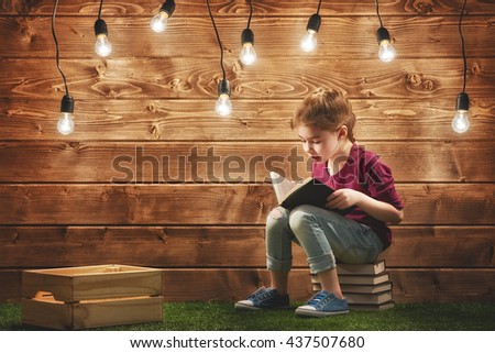 Cute little child girl reading a book.