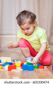 Cute Little Child Girl Sitting On The Floor And Playing With Building Blocks