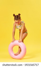 Cute Little Child Girl In Swimwear With Inflatable Rubber Ring On Yellow Background