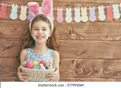 Cute little child girl wearing bunny ears on Easter day. Girl holding basket with painted eggs. - Powered by Shutterstock