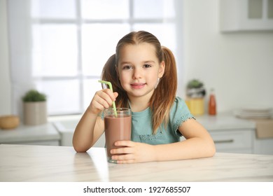 Cute Little Child With Glass Of Tasty Chocolate Milk In Kitchen