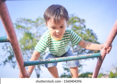 Cute Little Child Playing And Climbing On Iron Ladder In Public Kid Playground Alone.