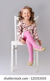 Cute Little Child Sitting On The Chair And Smiling. Wearing Pink Clothes