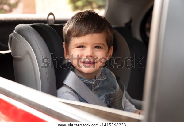 Cute little child sitting in safety seat\
inside car. Danger\
prevention