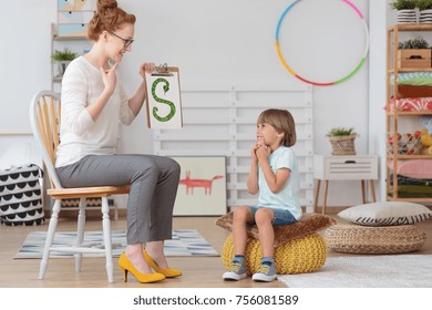 Cute Little Child With Speech Impediment And Smiling Young Preschool Teacher Learning The Alphabet Letters In Kindergarten Classroom