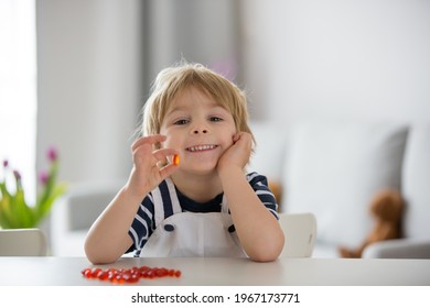 Cute little child, toddler boy, eating alfa omega 3 child supplement vitamin pills at home for better immunity