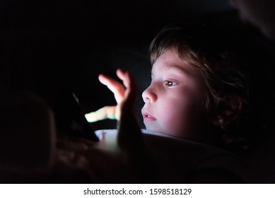 Cute Little Child Watching Cartoon On Smartphone In The Dark Room. Dangers Of Blue Light Damage His Eyes. Little Girl Can Get Age Related Macular Degeneration Of Blue Light.
