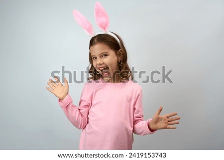 Cute little child wearing bunny ears on Easter day. Girl wearing pink bunny ears and shirt, white background with copy space