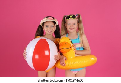 Cute Little Children In Beachwear With Bright Inflatable Toys On Pink Background