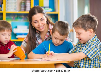 Cute Little Children Drawing With Teacher At Preschool Class