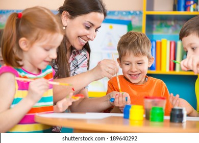Cute Little Children Drawing With Teacher At Preschool Class