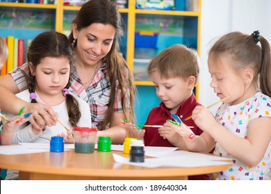 Cute Little Children Drawing With Teacher At Preschool Class