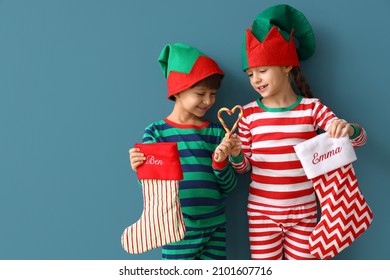 Cute little children in elves costumes and with Christmas socks on color background - Powered by Shutterstock