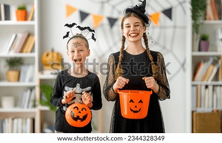 Cute little children girls in carnival costumes. Happy family preparing for Halloween. Funny kids at home.