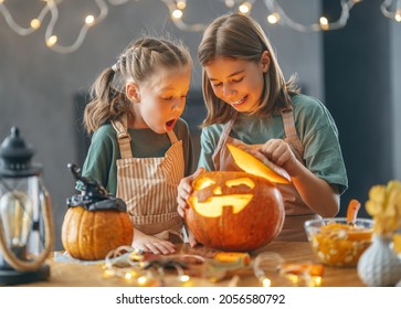 Cute little children girls with carving pumpkin. Happy family preparing for Halloween. 