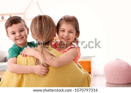 Cute little children hugging their nanny at home