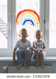 Cute little children on background of painting rainbow on window. Photo of kids leisure at home, childcare, safety joy symbol, family life. Brother and sister on vacation.