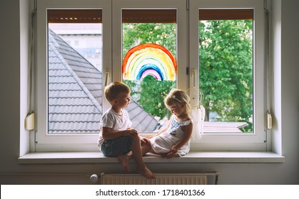 Cute Little Children On Background Of Painting Rainbow On Window. Photo Of Kids Leisure At Home, Safety Joy Symbol, Happy Childhood. Positive Visual Support During Quarantine. Family Art Background