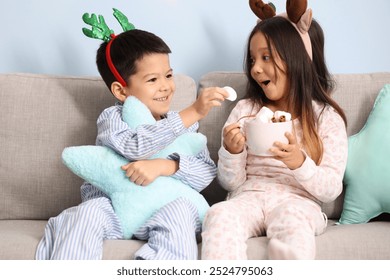 Cute little children in pajamas and with cup of tasty hot chocolate on Christmas eve at home - Powered by Shutterstock