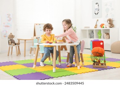 Cute little children playing with colorful toy pyramid at white table in kindergarten - Powered by Shutterstock