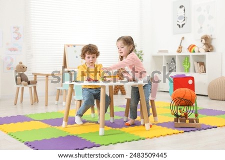 Cute little children playing with colorful toy pyramid at white table in kindergarten