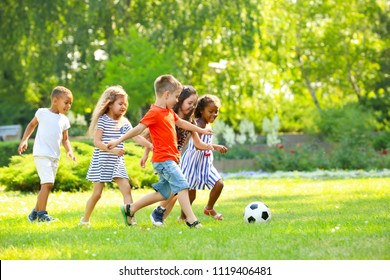 Kleine, süße Kinder spielen im Freien Fußball