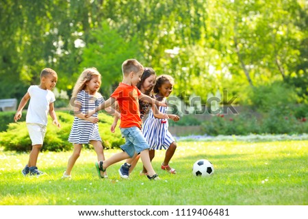 Cute little children playing football outdoors