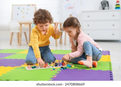 Cute little children playing with math game Fishing for Numbers on puzzle mat in kindergarten - Powered by Shutterstock