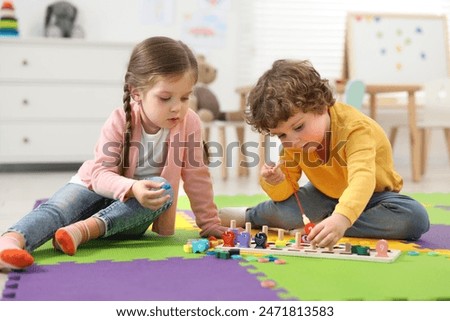 Cute little children playing with math game Fishing for Numbers on puzzle mat in kindergarten