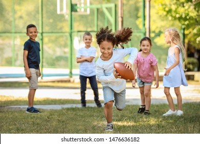 Cute Little Children Playing With Rugby Ball In Park