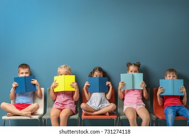 Cute little children reading books while sitting near color wall - Shutterstock ID 731274118