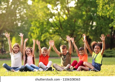Cute little children sitting on grass outdoors on sunny day