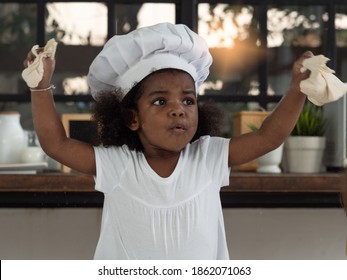 Cute Little Dark Skinned Girl Wearing Chef Hat Feeling Excited When Learning And Playing With Baking Dough.