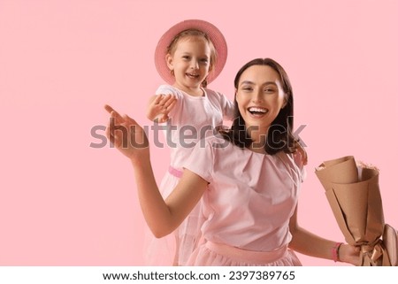 Cute little daughter greeting her beautiful mother with bouquet of roses on pink background. Happy  Mother's Day