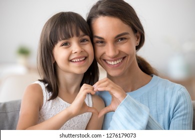 Cute Little Daughter And Happy Mother Join Hands In Shape Of Heart As Concept Of Mom And Child Love Care Support, Smiling Mum And Her Kid Girl Looking At Camera Posing Together For Headshot Portrait