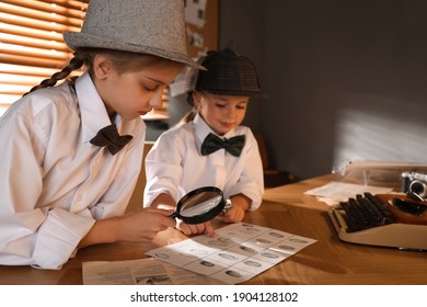 Cute Little Detectives Exploring Fingerprints With Magnifying Glasses At Table In Office