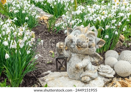 Cute little dragon, garden figurine to decorate the garden with spring flowers
