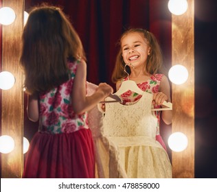 Cute Little Fashionista. Happy Child Girl Try On Outfits Looking At Mirror.