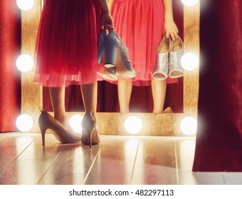 Cute little fashionista. Happy child girl try on outfits and mom's shoes looking at mirror.