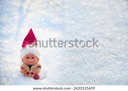 Cute little funny dwarf in the snow in the landscape in winter. Wizard on a snowy background. Christmas and New Year