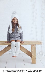 Cute little girl 5 years old wearing knitted trendy winter clothes posing over white brick wall