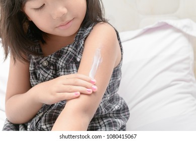 Cute Little Girl Applying  Body Lotion Cream On Her Arm After Shower. Selective Focus Healthcare And Skin Care Concept.