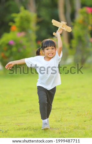 Cute little girl asia playing toy airplane on nature in the park. Little dreams of flying limitless imagination .Which increases the development and enhances learning skills.